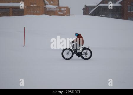 Mammoth Lakes, Californie. 27 février 2023. Un cycliste sur une pédale électrique sur une route enneigée pendant un blizzard d'hiver. Banque D'Images