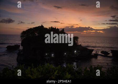 Photo de tout le temple de Pura Tanah Lot, prise d'en haut complètement entouré par la mer, avec un ciel de coucher de soleil en arrière-plan. Banque D'Images