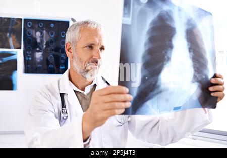 HES le radiologue de passage. un médecin de sexe masculin mature examinant une image radiologique. Banque D'Images