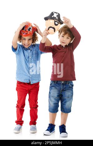 Tout ce qui est prêt à jouer. Photo studio de deux petits garçons portant des masques sur fond blanc. Banque D'Images