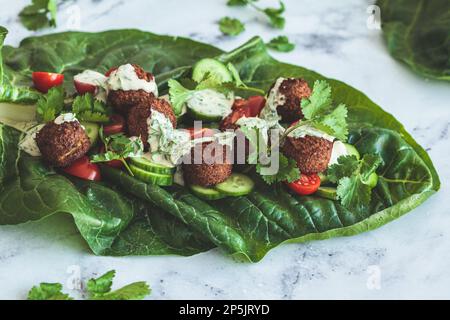 Envelopper le falafel avec les légumes et le tahini sur la laitue verger verte. Recette végétalienne alternative. Banque D'Images