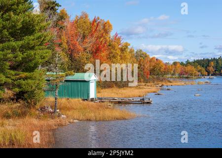 Un hangar à bateaux sur le lac Moosehead. Forêt aux couleurs d'automne en arrière-plan, comme vu depuis le barrage de Rockwood. Pic de feuillage en Nouvelle-Angleterre. Rockwood, Maine, États-Unis. Banque D'Images