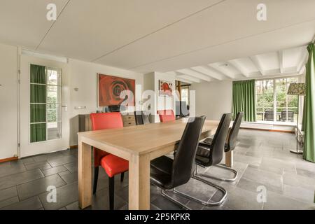 Amsterdam, pays-Bas - 10 avril 2021 : une table et des chaises dans une salle avec des rideaux verts sur le mur derrière elle est une grande fenêtre Banque D'Images