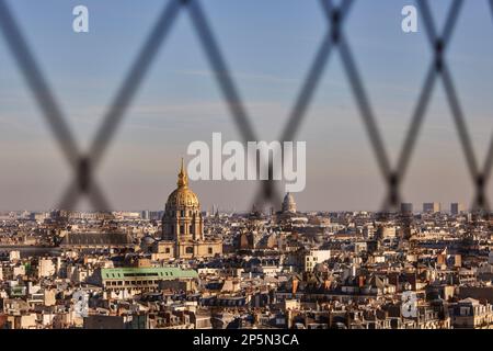 Monument parisien, toits encadrant le dôme doré des Invalides et la tombe de Napoléon à travers le maillage de la Tour Eiffel Banque D'Images