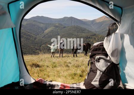 Couple et cheval en montagne, vue depuis la tente de camping Banque D'Images