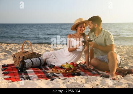 Couple charmant pique-nique sur une plage de sable près de la mer Banque D'Images