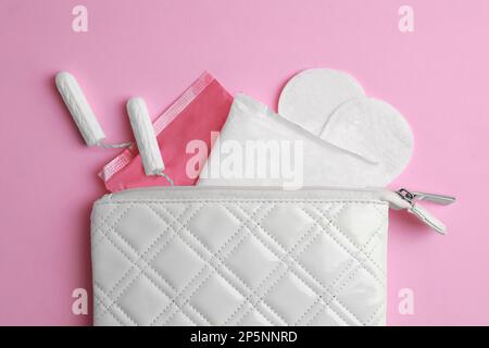 Sac avec tapis menstruels, tampons et pantyliners sur fond rose, couché à plat Banque D'Images