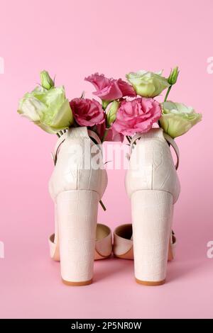 Chaussures à talons hauts pour femmes élégantes avec de belles fleurs sur fond rose Banque D'Images