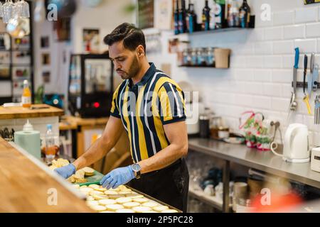Jeune homme préparant des aliments frais dans une cuisine commerciale Banque D'Images