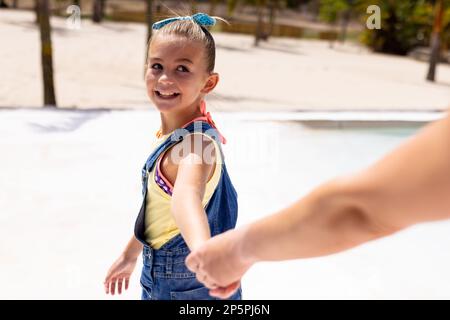 Bonne mère et fille biraciale marchant et tenant les mains à la plage Banque D'Images