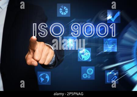 Homme pointant vers l'écran virtuel avec le texte ISO 9001 et différentes icônes, gros plan Banque D'Images