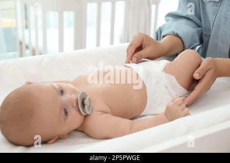 La mère change la couche de son bébé sur la table à la maison Banque D'Images