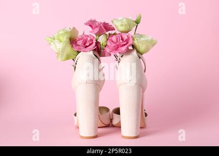 Chaussures à talons hauts pour femmes élégantes avec de belles fleurs sur fond rose Banque D'Images