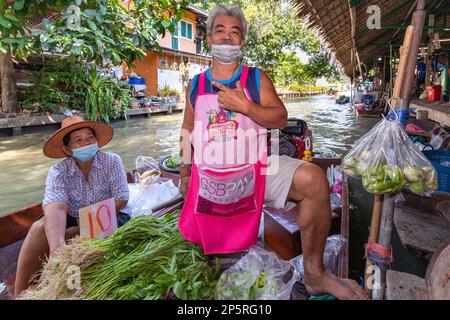 Des thaïlandais se font nourrir en bateau à longue queue au marché flottant de Lad Mayom, Bangkok, Thaïlande Banque D'Images