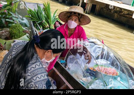 Des thaïlandais se font nourrir en bateau à longue queue au marché flottant de Lad Mayom, Bangkok, Thaïlande Banque D'Images