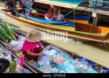 Des thaïlandais se font nourrir en bateau à longue queue au marché flottant de Lad Mayom, Bangkok, Thaïlande Banque D'Images