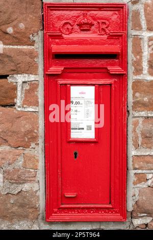 Une boîte de poteau George V montée dans un mur de grès rouge dans le village d'Edenhall, Cumbria, Royaume-Uni Banque D'Images