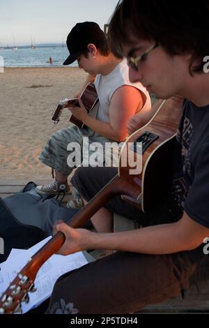 Roses. Deux amis à jouer de la guitare dans Gran beach.Costa Brava. Province de Gérone. La Catalogne. Espagne Banque D'Images