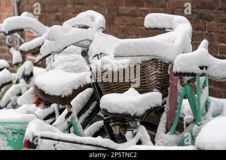 Vélos garés couverts de neige avec profondeur de champ dans une allée de Dordrecht aux pays-Bas. Scène urbaine typique des pays-bas en hiver. Banque D'Images