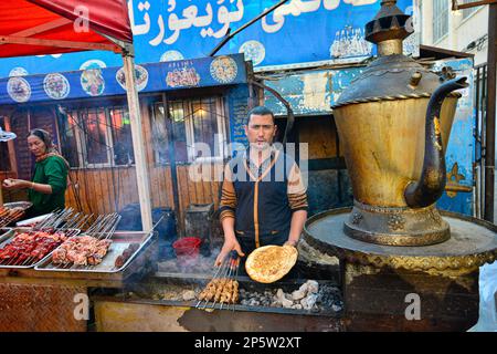 Vendeurs vendant de la viande cuite au barbecue et de la nourriture locale Uighour sur un marché traditionnel à Urumqi, Xinjiang, Chine Banque D'Images