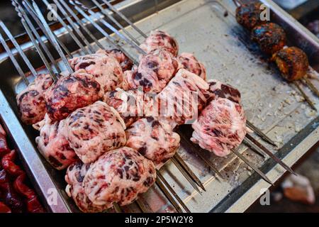 Vendeurs vendant de la viande cuite au barbecue et de la nourriture locale Uighour sur un marché traditionnel à Urumqi, Xinjiang, Chine Banque D'Images