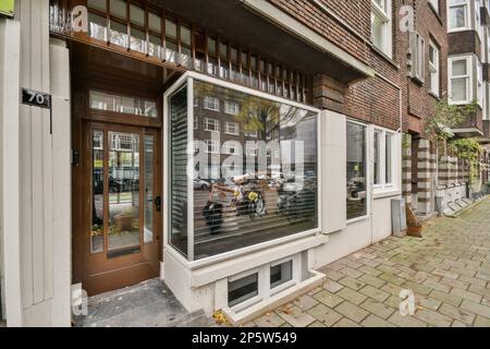 Amsterdam, pays-Bas - 10 avril 2021 : un bâtiment avec des personnes dans la fenêtre et quelques voitures garées de l'autre côté de la rue, vu de l'extérieur Banque D'Images