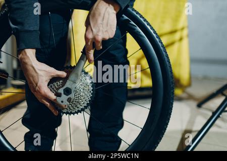 Mécanicien réparateur assemblant la transmission du pignon d'engrenage serrez la barre de poignée du vélo personnalisé dans l'atelier Banque D'Images