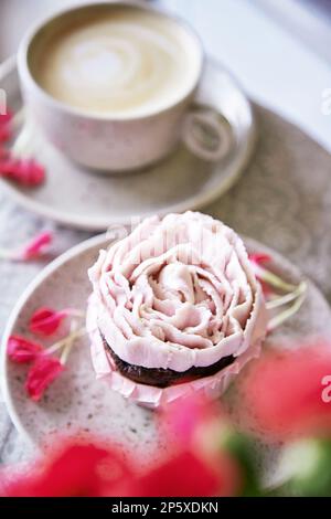 Cupcake rose esthétique avec une tasse de café. Décoration de fleurs. Nourriture de vacances fond festif. Banque D'Images