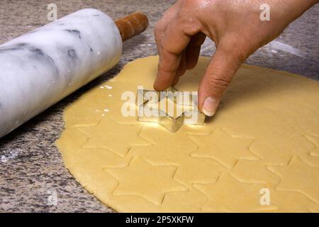 Cuisson des biscuits de Noël, la forme en étoile est pressée dans la pâte Banque D'Images