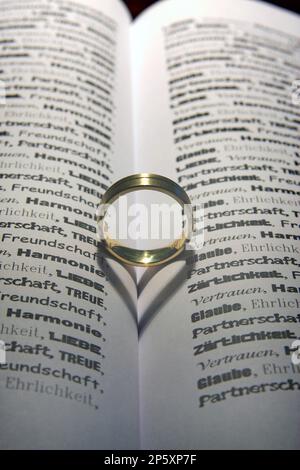 bague dorée dans un livre ouvert qui ombre un coeur Banque D'Images