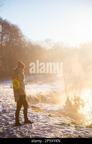 Les femmes se trouvent dans la neige près du lac d'hiver Banque D'Images