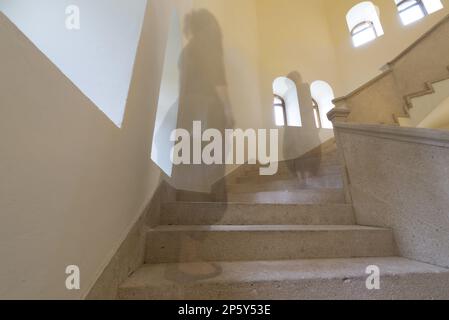 Femme en exposition longue marchant dans les escaliers avec des fenêtres. Banque D'Images