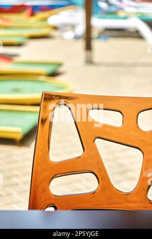 Dossier de chaise en verre acrylique transparent sur fond flou. Endroit pour s'asseoir dans la rue touristique café près du parc aquatique le jour ensoleillé de la fermeture Banque D'Images