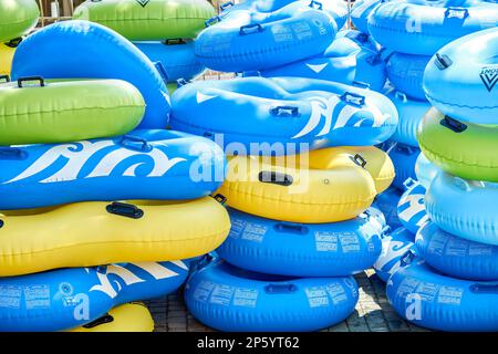 Anneaux en caoutchouc multicolores pour la piscine mis en rangées à la lumière du soleil. Piles de maillots de bain gonflables prêts pour les touristes dans le parc aquatique Banque D'Images