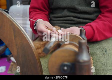 Un artiste de la rue à coudre la fabrication avec la roue de rotation traditionnelle. Couture de fibres artisanales par machine vintage. Banque D'Images