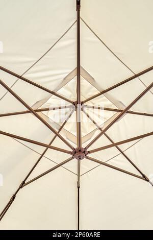 Parapluie beige clair protège les visiteurs du café des rayons du soleil près de la prise de vue en angle bas. Accessoire pour la décoration et l'atmosphère des lieux publics Banque D'Images