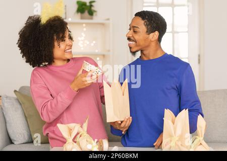 Couple noir emballage des œufs de Pâques au chocolat dans un sac de papier artisanal à la maison Banque D'Images