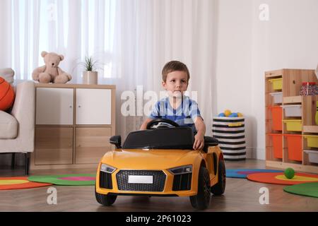 Petit enfant jouant avec une voiture-jouet dans la chambre Banque D'Images