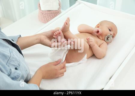 La mère change la couche de son bébé sur la table à la maison Banque D'Images