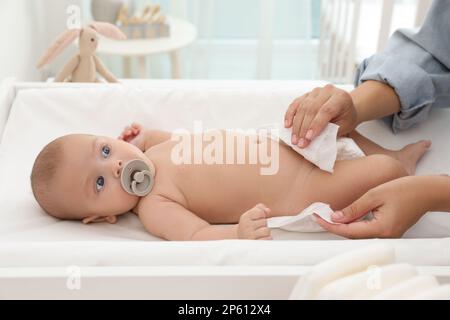 La mère change la couche de son bébé sur la table à la maison Banque D'Images