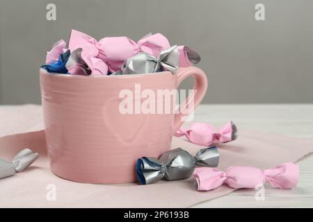 Bonbons dans des emballages colorés sur une table en bois blanc Banque D'Images