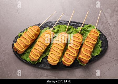 Délicieux chiens de maïs avec moutarde sur table grise, vue de dessus Banque D'Images