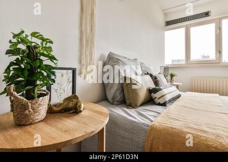 une chambre à coucher avec deux lits et une plante sur la table latérale devant le lit qui est à côté de la fenêtre Banque D'Images