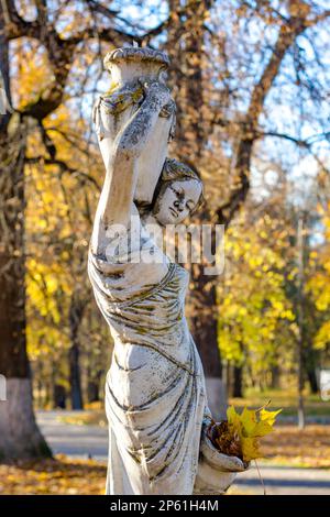 Obninsk, Russie - octobre 2017 : sculpture de parc d'une femme de style ancien avec des cruches et parmi le feuillage d'automne. Parc Belkino Banque D'Images