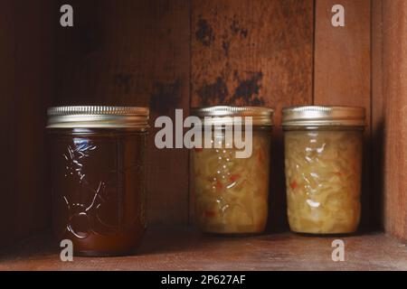 Confiture de fraises et relish conservées dans des pots de maçon sur une étagère en bois rustique Banque D'Images