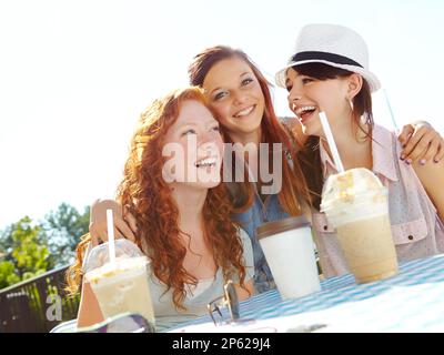 Partager le printemps de leur vie. Un groupe d'adolescentes qui apprécient les smoothies dans un café en plein air. Banque D'Images