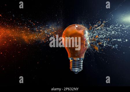 explosion d'une ampoule orange sur fond noir Banque D'Images