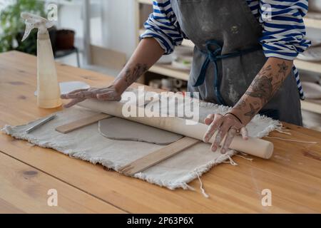 Mains artisan femme de traitement de l'argile avec rouleau en bois pour faire la vaisselle originale faite à la main Banque D'Images