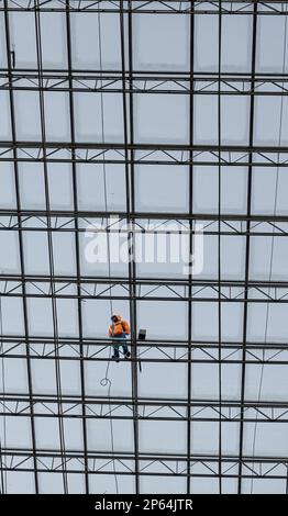 Homme travailleur nettoyant plafond en verre Banque D'Images