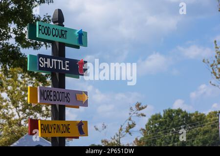 Des panneaux en bois peints sur un poteau donnent des informations et des directions avec des flèches lors d'un festival d'automne. Banque D'Images